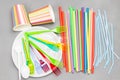 Bright colourful plastic tableware. Plastic spoons, forks, straws on plate. Paper colored glasses Royalty Free Stock Photo