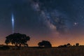 A bright comet in the night sky over an open field with trees Royalty Free Stock Photo