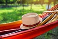 Bright comfortable hammock with hat hanging in garden, closeup