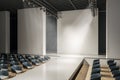 Bright concrete auditorium interior with seats, runway and empty mock up place on wall. Presentation and fashion concept. Royalty Free Stock Photo