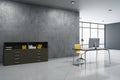 Bright concrete office interior with desktop and computer, other pieces of furniture and objects, window with city view. 3D