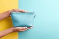Bright cosmetic bag presented on a cheerful backdrop with clear space for text and emphasis on hands Royalty Free Stock Photo