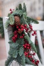 A white wooden bench in the park is decorated with fir branches with cones and red berries. New Year theme. Royalty Free Stock Photo