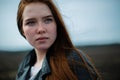 A bright, defiant woman with long red hair looks up proudly.