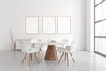 Bright dining room interior with table, three empty white posters