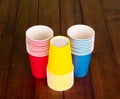 Bright disposable cups on background of dark wood.