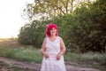 Bright diversity woman with pink hair portrait. Girl squatted down on a forest path into the sunset