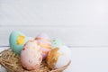 Bright easter eggs with in basket, on white wood