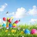 Bright Easter eggs and flowers in grass against blue background, space for text Royalty Free Stock Photo