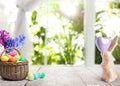 Bright Easter eggs in wicker basket and bunny figure on table Royalty Free Stock Photo
