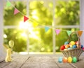 Bright Easter eggs in wicker basket and bunny figure on table Royalty Free Stock Photo