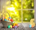 Bright Easter eggs in wicker basket and bunny figure on table Royalty Free Stock Photo