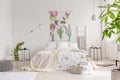 A bright eco friendly bedroom interior with a bed dresses in green plants pattern white linen. Fabric painted in flowers and birds Royalty Free Stock Photo