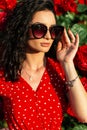 bright elegant portrait of a beautiful young slender curly-haired Italian girl with vintage sun glasses in a retro red dress with Royalty Free Stock Photo