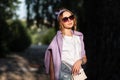 Bright fashion portrait of sensual beautiful young woman with sunglasses in a white t-shirt and jeans shorts with a purple hoodie Royalty Free Stock Photo