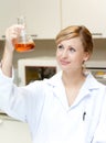 Bright female scientist looking at an erlenmeyer