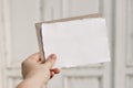 Bright feminine stationery mockup scene. Closeup of woman hand holding handmade paper greeting card, envelope. Blurred Royalty Free Stock Photo