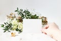 Bright feminine wedding stationery mockup scene. Closeup of woman hand holding paper place card. Bouquet of eucalyptus