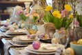 Bright festive table setting for Easter with rabbit, spring bouquets of flowers, decorative eggs and colorful dishes Royalty Free Stock Photo