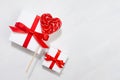 Bright festive wedding background - white gift boxes with red bow, sweet lollipops hearts on white wood board, border.