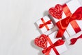 Bright festive wedding background - white gift boxes with red bow, sweet lollipops hearts on white wood board, border, closeup.