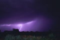 Bright flash of lightning illuminated the night sky and dyed clouds in a blue violet color Royalty Free Stock Photo