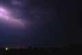 Bright flash of lightning illuminated the night sky and dyed clouds in a blue violet color Royalty Free Stock Photo