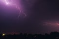 Bright flash of lightning illuminated the night sky and dyed clouds in a blue violet color Royalty Free Stock Photo