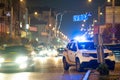 Bright flashing blue lights of police patrol car parked on city street with night traffic Royalty Free Stock Photo