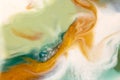 Bright flowing alcohol Ink gold colors on blue green background. Acrylic Fluid Art. Liquid marble texture for abstract artwork. Royalty Free Stock Photo