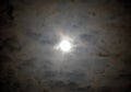 Bright full moon glowing beneath a circle of sppoky ethereal clouds glowing orange