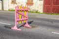 Bright funny pink-yellow wooden barrier on the road