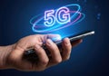 A bright 5G logo surrounded by neon rings on the smartphone held in hand. High-speed mobile technology Royalty Free Stock Photo
