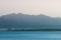 Bright gentle pink sunrise on sea with mountains in haze, green rain forest on horizon, shine blue calm sea with breeze. Indonesia Royalty Free Stock Photo