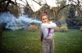 A bright girl with glitter makeup and African braids in a bluish shirt takes refuge in artificial smoke in a park full Royalty Free Stock Photo