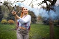 A bright girl with glitter makeup and African braids in a bluish shirt takes refuge in artificial smoke in a park full Royalty Free Stock Photo