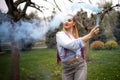 A bright girl with glitter makeup and African braids in a bluish shirt takes refuge in artificial smoke in a park full Royalty Free Stock Photo