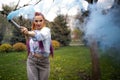 A bright girl with glitter makeup and African braids in a bluish shirt takes refuge in artificial smoke in a park full Royalty Free Stock Photo