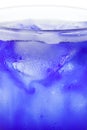 Bright glass refreshing beverage with melting ice cubes in blue syrop and condensation on its wall isolated white background macro Royalty Free Stock Photo