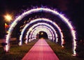 Bright glowing arch of colored lanterns in the park in the evening