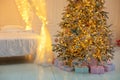 Bright glowing Christmas tree in living room in evening. Christmas tree with lights glowing garlands and gifts. Royalty Free Stock Photo