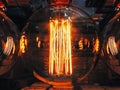 Bright glowing clear glass lamp spherical shape close up. Illumination edison retro lamp dark background. Antique