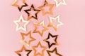 Bright gold glossy stars on soft light pink color, top view, border.