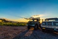 Bright gold sunset shines on heavy duty trucks and farmlands