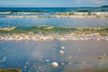 Bright golden sunset on the beach, the waves on the sand, shells.