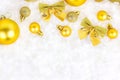 Bright golden Xmas decorations ribbons, baubles, bows, ornament flat lay on white artificial snow background with copy space. Royalty Free Stock Photo