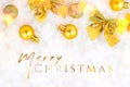 Bright golden Xmas and New Year decorations baubles, bows, ornament on white artificial snow background with Merry Christmas Royalty Free Stock Photo