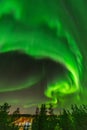 Bright green aurora lights almost on the whole sky over tree tops in Sweden, river, city lights and lake, clear skies with a lot Royalty Free Stock Photo