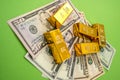 on a bright green background lie dollar bills with gold bars on top of them Royalty Free Stock Photo