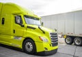 Bright green big rig semi truck with grille guard standing on truck stop beside with another trucks with semi trailers Royalty Free Stock Photo